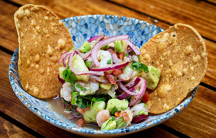 Tosta de camarón con aguacate, cebolla morada, cilantro y tostadas crujientes en un bol.