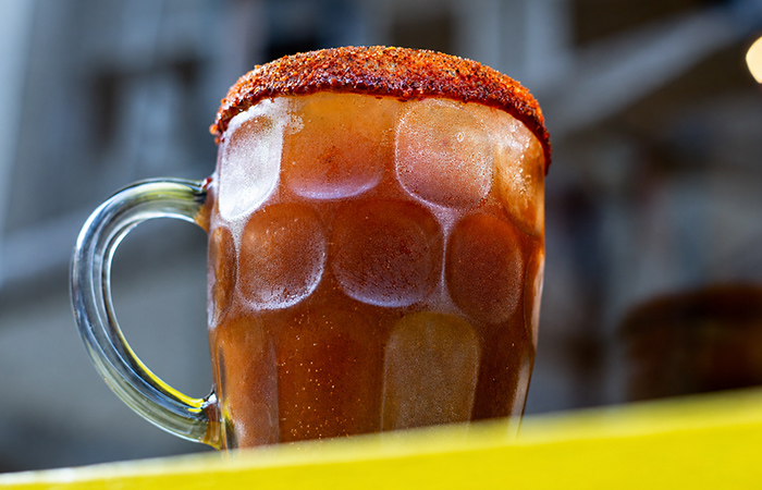Michelada mexicana servida en jarra fría con borde de chile y especias.