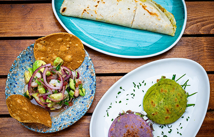 Platos mexicanos variados Platos mexicanos variados con tosta de camarón, quesadilla y guacamole servidos sobre una mesa de madera.